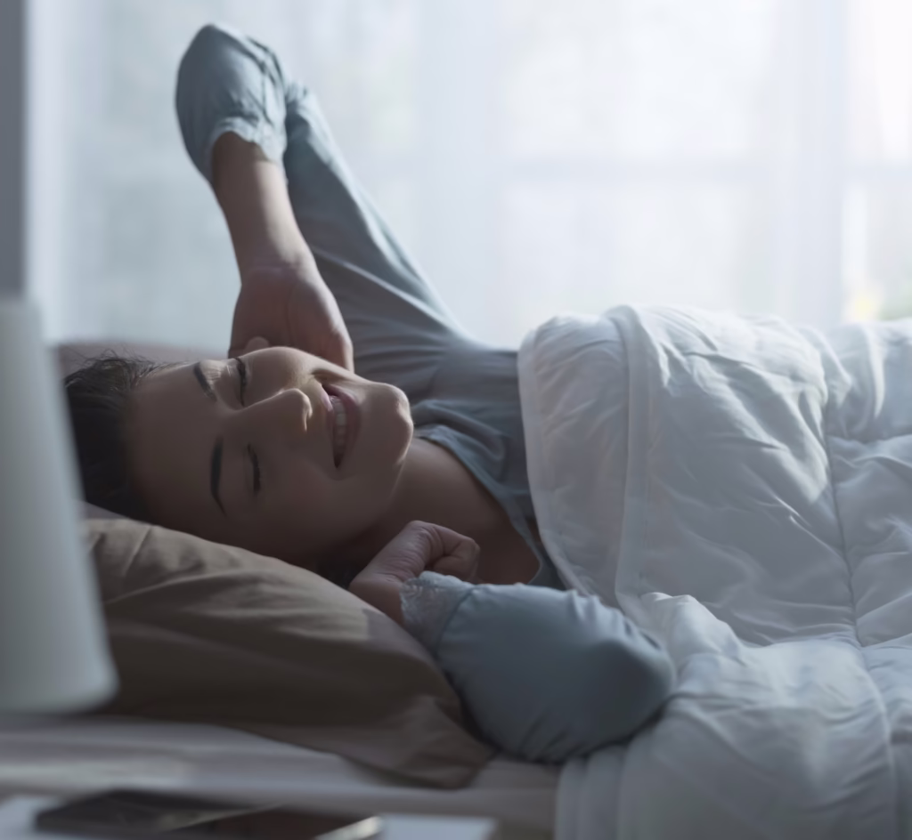 Person sleeping peacefully in bed with soft morning light, representing restorative sleep and recovery.