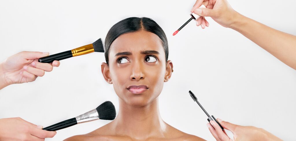 Woman surrounded by makeup tools, symbolizing that true glowing skin comes from cellular health rather than surface beauty products.