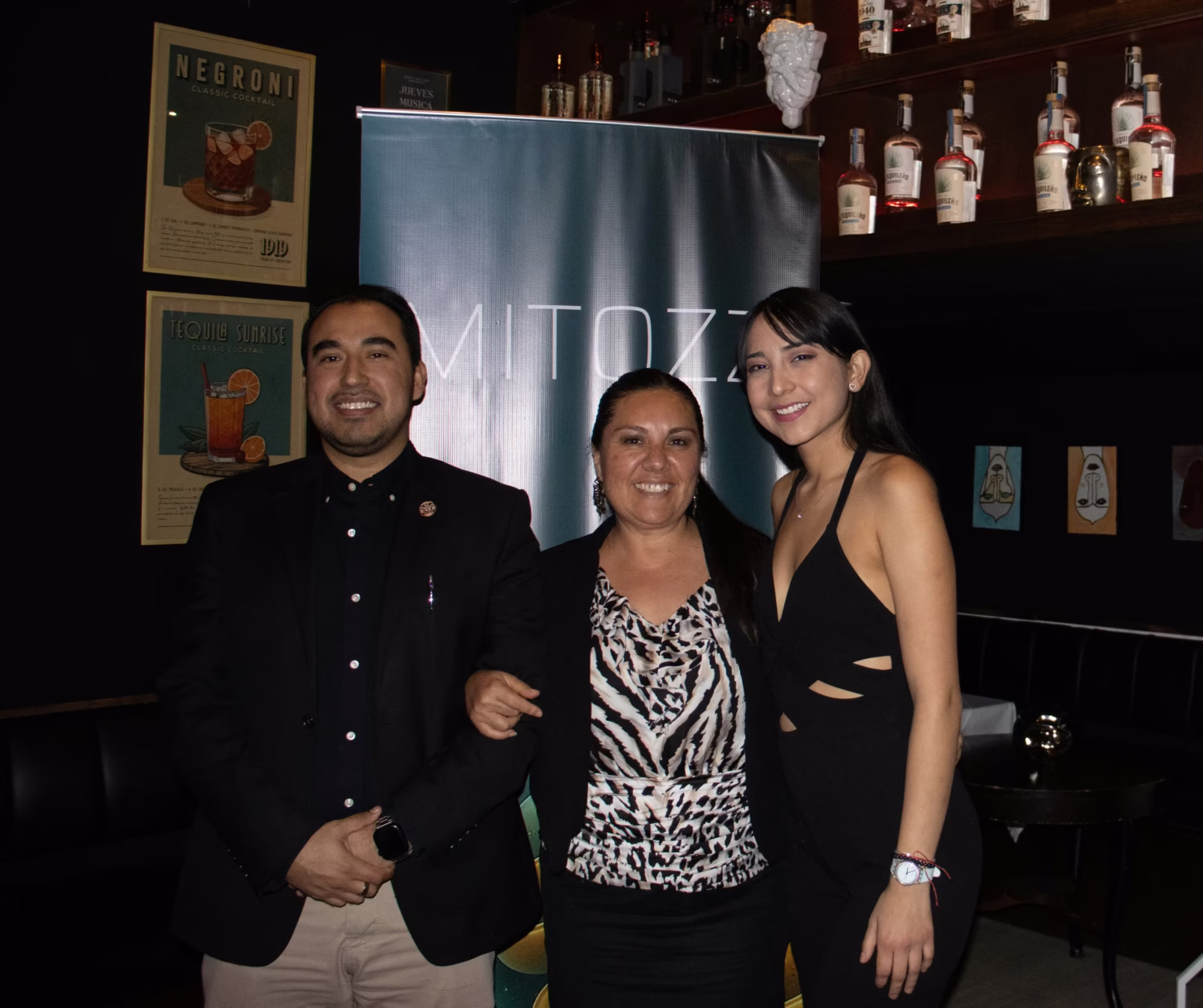 Group of guests posing together at a Mitozz brand event held at Talento restaurant, with a Mitozz banner displayed in the background.