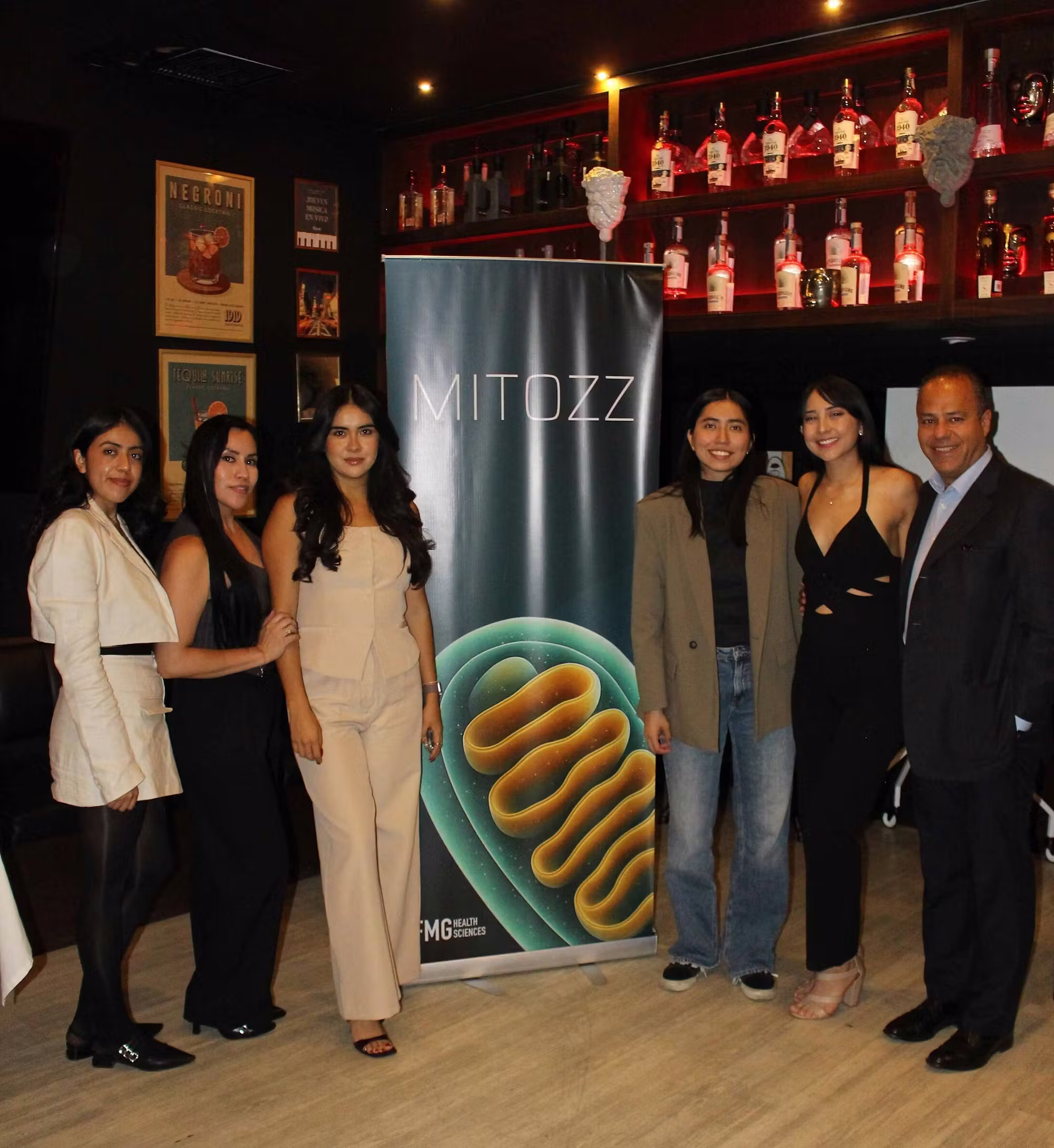 FMG personnel standing next to a vertical Mitozz banner featuring a mitochondria graphic during an event at Talento restaurant.