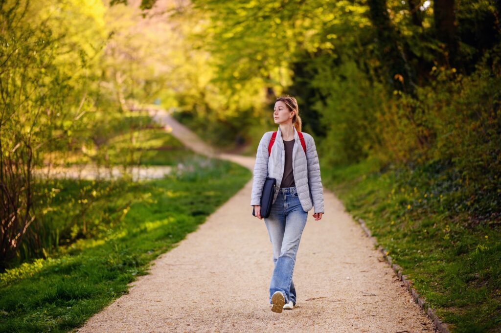 Person walking outdoors on a path, illustrating daily movement as a simple habit that supports blood flow and arterial health.