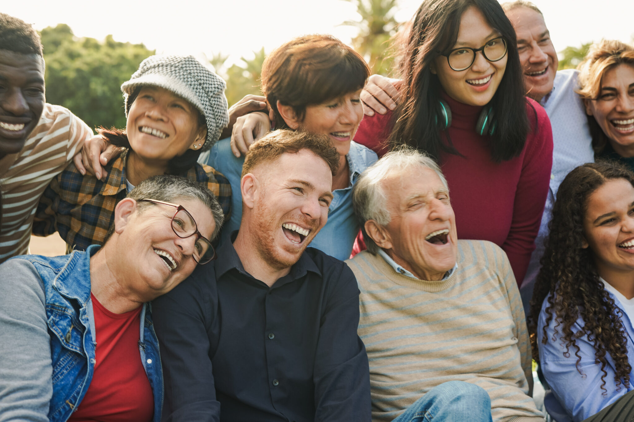 Close-up of a diverse, multigenerational group of friends laughing together outdoors as happy Mitozz customers in a sunny park. (-)-epicatechin, FMG Health Sciences