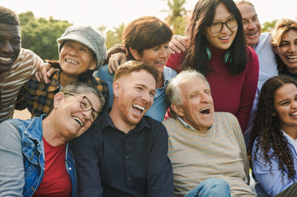 Close-up of a diverse, multigenerational group of friends laughing together outdoors as happy Mitozz customers in a sunny park. (-)-epicatechin, FMG Health Sciences