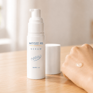 Mitozz RS serum bottle with cap beside it and a small amount of serum on the back of a hand in soft natural light.