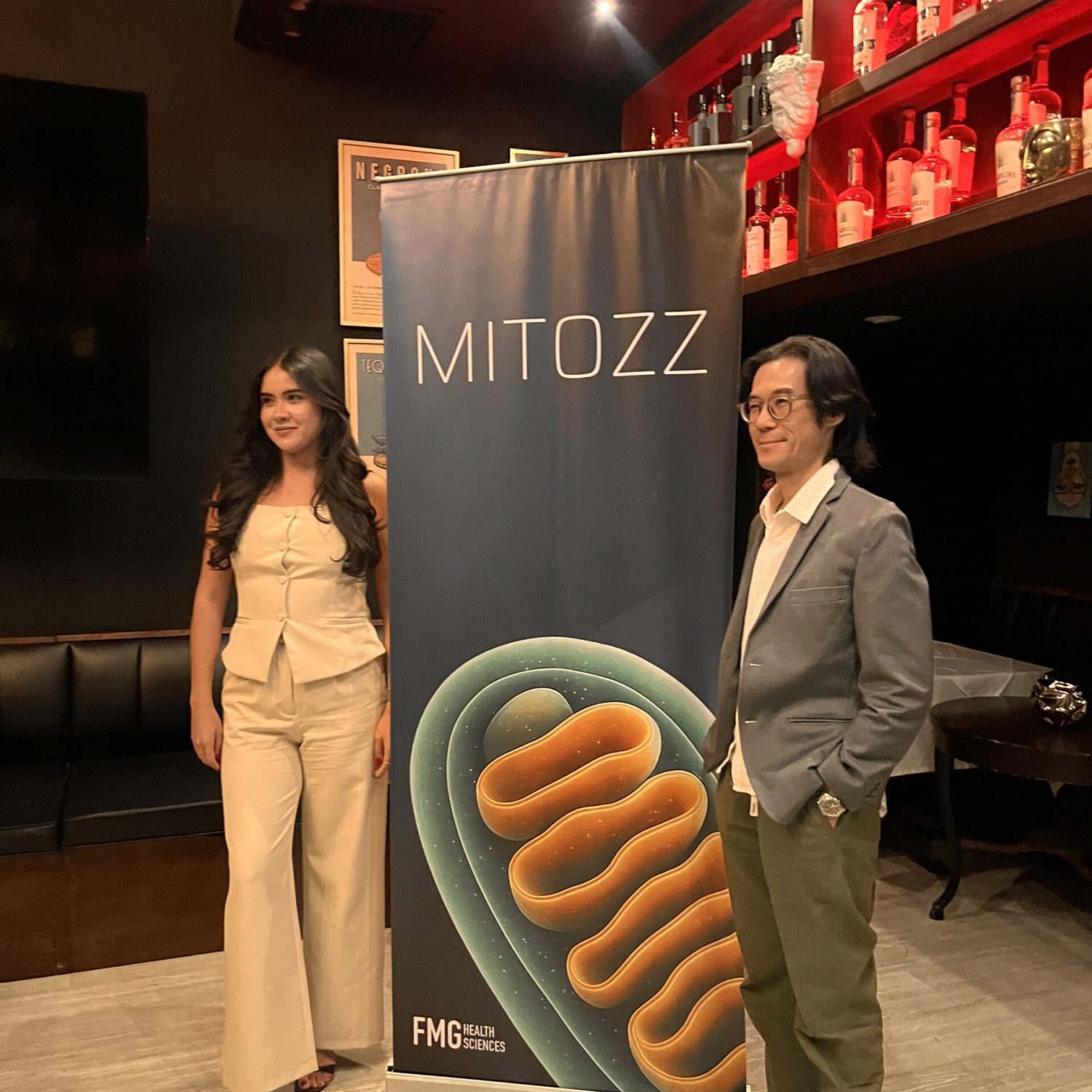 Guests at Mitozz Events posing in front of the mitochondrial health banner during a wellness gathering.